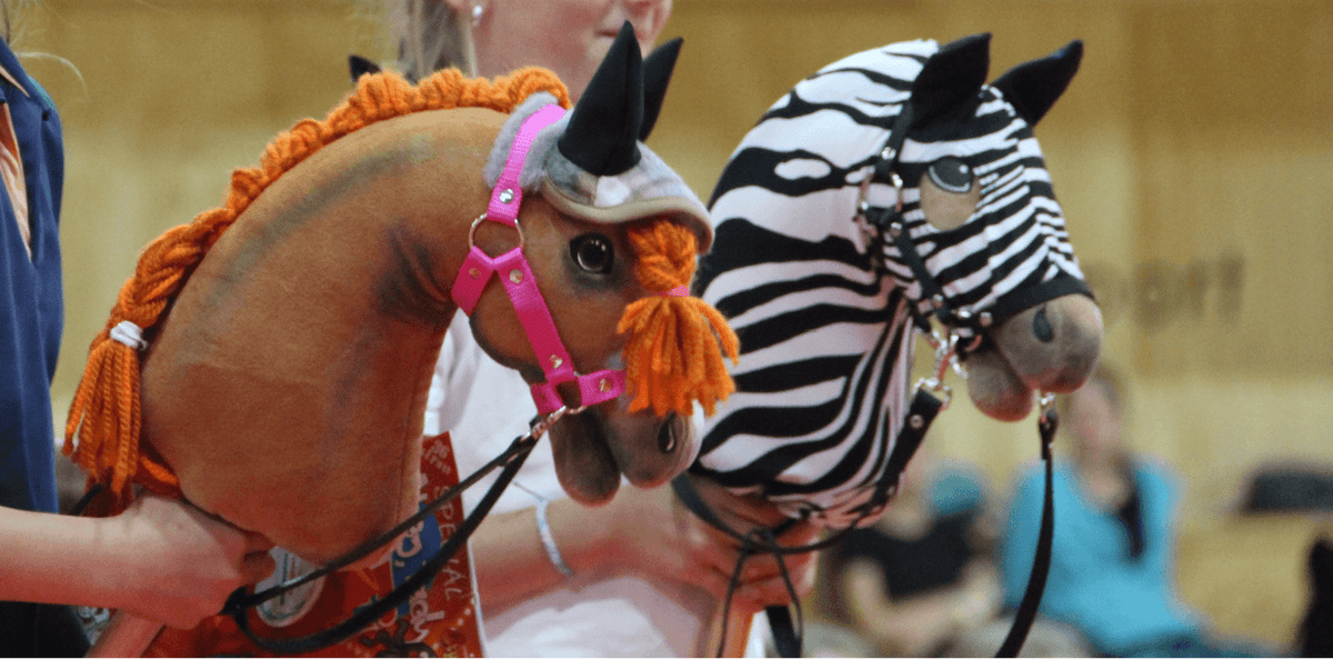 Two Hobby Horses with braided manes, one brown with orange yarn and one zebra patterned
