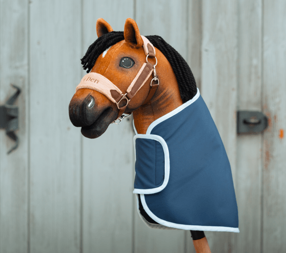Hobby Horse LarDen portant une Couverture bleue bordée de blanc et un Licol