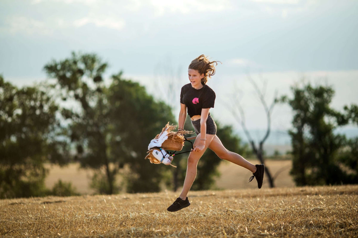 Jeune fille sautant en extérieur avec un Hobby Horse pendant un entraînement de Hobby Horsing