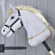 Hobby Horse LarDen gris avec bridon noir, crinière dorée et Cordéo Nature fait main, suspendu à un bâton en bois devant un mur gris. Une corde jaune en polypropylène est passée en boucle autour de son cou.