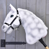 The Hobby Horse LarDen "Elektra" features a plush white design with blue eyes, a black halter, and is mounted on a stick, shown here against a gray wooden wall.