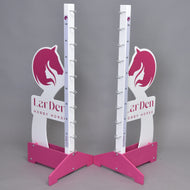 Deux montants LarDen jump 110 cm / 43 inch roses et blancs de Hobby Horse LarDen avec motifs de tête de cheval, repères de hauteur réglables et supports métalliques pour barre, sur fond gris. « LarDen HOBBY HORSE » est imprimé sur la base.