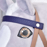Gros plan sur un jouet Hobby Horse LarDen montrant la Bride complète avec muserolle Marron Violet : œil en tissu détaillé, bride en similicuir violet foncé, sangle beige et pelage doux gris clair.