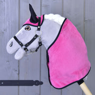 Hobby Horse gris sur bâton de Hobby Horse LarDen, avec l’Ensemble Rose Fuchsia (bonnet d'oreilles + couverture) et une bride noire, placé devant une clôture en bois.
