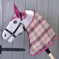 Ensemble Cube Rose de Hobby Horse LarDen, sur un Hobby Horse en peluche au visage gris avec bride noire et couverture à carreaux beige, rose et noir, présenté devant un mur en bois.