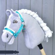 Hobby Horse gris et blanc à crinière blanche tressée portant le Licol turquoise avec fourrure de Hobby Horse LarDen, l'accessoire parfait, sur fond en bois gris clair.