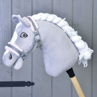 Licol gris avec fourrure rose de Hobby Horse LarDen sur un cheval gris en peluche avec crinière blanche et licol gris, fixé à un bâton en bois devant un fond de panneaux en bois gris.