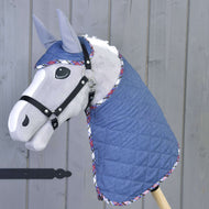 Ensemble Jean de Hobby Horse LarDen sur un Hobby Horse gris avec couverture matelassée bleue et bonnet d’oreilles assorti bordé de carreaux, le tout monté sur un bâton en bois devant un fond en bois gris.
