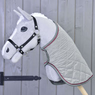 Hobby Horse en peluche gris de Hobby Horse LarDen avec bride noire et Couverture Argent Élégance, devant un mur en bois à panneaux verticaux.
