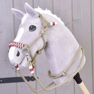 Un Hobby Horse en peluche gris avec crinière blanche et liste blanche, portant l’Ensemble de cordes Élégance de Hobby Horse LarDen, devant un mur en bois clair.