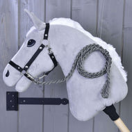 Hobby Horse - Corde d'attache tricotée Graphite de Hobby Horse LarDen, tête en peluche grise avec bride noire et longe graphite tricotée à la main sur un bâton en bois, présentée devant un mur en bois gris.