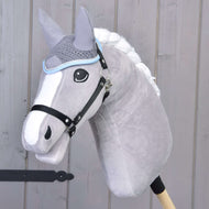 Bonnet d’oreilles gris en crochet de Hobby Horse LarDen présenté sur un Hobby Horse en peluche gris avec une crinière blanche et une bride noire, monté sur un bâton en bois devant un mur en bois clair.