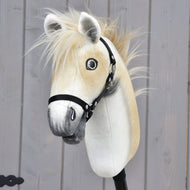 The Hobby Horse LarDen Honey Pearl with Black Halter (size S) is a plush Oldenburg-style hobby horse, featuring a beige mane, gray muzzle, and black halter, mounted on a stick before a gray wooden wall.