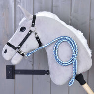 Hobby Horse - Corde d'attache tricotée double bleue de Hobby Horse LarDen, cheval en peluche gris avec bride noire et longe bleue tricotée à la main avec mousqueton de qualité supérieure, présenté devant un mur en bois.