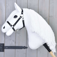Hobby Horse Lady avec licol noir de Hobby Horse LarDen, avec tête de cheval blanche, longue crinière en fil, licol noir et grands yeux noirs sur bâton en bois, présenté sur fond en bois gris.