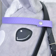 Gros plan sur la tête d’un jouet en peluche Hobby Horse LarDen portant la Bride complète sans muserolle Violet clair, avec sangle violette à motif hexagonal, bouton métallique et rênes amovibles sur pelage gris et blanc.