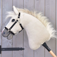 Hobby Horse Pixie avec licol noir de Hobby Horse LarDen, avec design Akhal-Teke beige en peluche, crinière blanche, licol noir et bâton en bois, présenté devant un mur en bois gris clair.