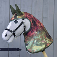 Imperméable Galaxie de Hobby Horse LarDen sur un Hobby Horse gris réaliste avec bride noire et couvre-tête et couvre-encolure style imperméable tout temps à effet marbré vert, rouge et crème, présenté sur fond en bois.