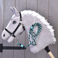 Hobby Horse gris à crinière blanche tressée et licol noir, la longe rayée verte accrochée sous le menton