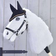 Hobby Horse gris de Hobby Horse LarDen avec rênes noires et crinière blanche portant le Bonnet d’oreilles au crochet Noir Or pour la protection contre les insectes, avec détails noirs sur le visage, sur fond en bois clair.