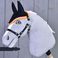 Gros plan sur un Hobby Horse LarDen gris avec bride et bonnet d’oreilles au crochet Drapeau pour la protection contre les insectes, avec œil détaillé, crinière blanche, oreilles noires et bonnet bordé d’orange, sur fond en bois.