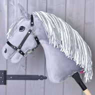 Hobby Horse Calypso gris avec licol noir de Hobby Horse LarDen, inspiré du Dutch Warmblood, avec crinière blanche en fil et monté sur un bâton en bois, appuyé contre un mur en bois clair.
