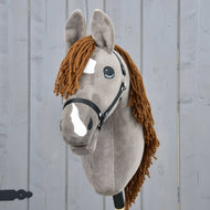 Hobby Horse Chanell avec licol noir de Hobby Horse LarDen, avec robe grise, crinière en fil brun, taches blanches sur le visage et grands yeux expressifs, présenté devant un fond en bois gris.