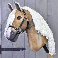 The Hobby Horse LarDen's Hobby Horse Connie with Black Halter features a realistic light tan face, white blaze, black halter, and long white yarn mane on a wooden stick, displayed against a gray wooden wall.