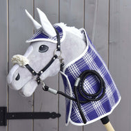 Ensemble Cube (couverture, bonnet d'oreilles, longe, licol avec fourrure) de Hobby Horse LarDen, comprenant une couverture, un bonnet d’oreilles, une longe et un licol en fourrure, présenté sur un mur en bois près d’une charnière de portail noire. Les accessoires mettent en valeur la qualité et le charme des produits Hobby Horse LarDen.