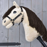 Hobby Horse Frederik LD avec licol noir de Hobby Horse LarDen, avec tête de Mustang en peluche, crinière en fil brun, licol noir et rênes sur un bâton, présenté devant un fond de planches en bois.