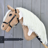 The Hobby Horse LarDen Fury with Black Halter features a light brown face, white patches, a long white mane, and is mounted on a wooden stick, shown here against a gray wooden wall.