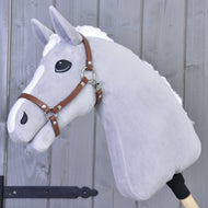 Hobby Horse LarDen gris en peluche avec crinière blanche et marques sur le nez, portant un Licol - similicuir marron, monté sur un bâton en bois et présenté devant un mur en bois gris.