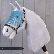 Hobby Horse LarDen gris avec licol noir à franges turquoise devant un mur en bois.