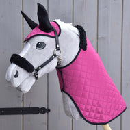 Ensemble Beauté Rose (bonnet d'oreilles + couverture + licol avec fourrure) de Hobby Horse LarDen sur un Hobby Horse en peluche avec couverture rose matelassée, bonnet d'oreilles assorti et licol bordé de fourrure, accessoires essentiels, posé devant des planches en bois.
