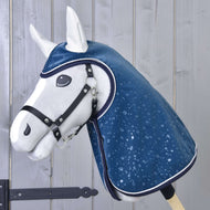 Hobby Horse LarDen "Raincoat Derby", hobby horse blanc en peluche avec licol noir et imperméable bleu brillant décoré de gouttes d’eau, présenté sur fond de planches en bois clair.