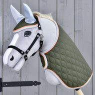 Ensemble Moos de Hobby Horse LarDen avec Hobby Horse gris, bride noire, couverture matelassée verte et bonnet d'oreilles bleu clair sur un bâton en bois, présenté devant un mur en bois gris.