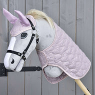 Ensemble Cœur le Plus Doux de Hobby Horse LarDen avec hobby horse en peluche au visage gris clair, bride noire, crinière claire, oreilles roses avec bonnet d'oreilles et couverture rose matelassée, présenté sur un fond en bois.