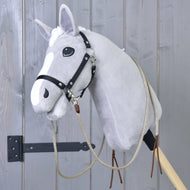 Rênes Western Fendues Dallas de Hobby Horse LarDen sur un Hobby Horse gris en peluche avec bride noire, monté sur un bâton en bois devant un mur en bois gris.