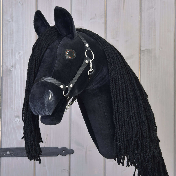 Hobby Horse noir avec longue crinière noire en fil et bride, monté sur un fond en bois avec une charnière en métal foncé.