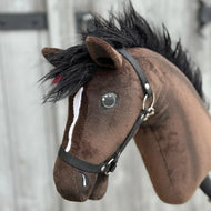 Gros plan sur Hobby Horse Lucas avec licol noir de Hobby Horse LarDen, un étalon hanovrien marron avec crinière noire, liste blanche sur le visage et licol noir, sur fond en bois flou.