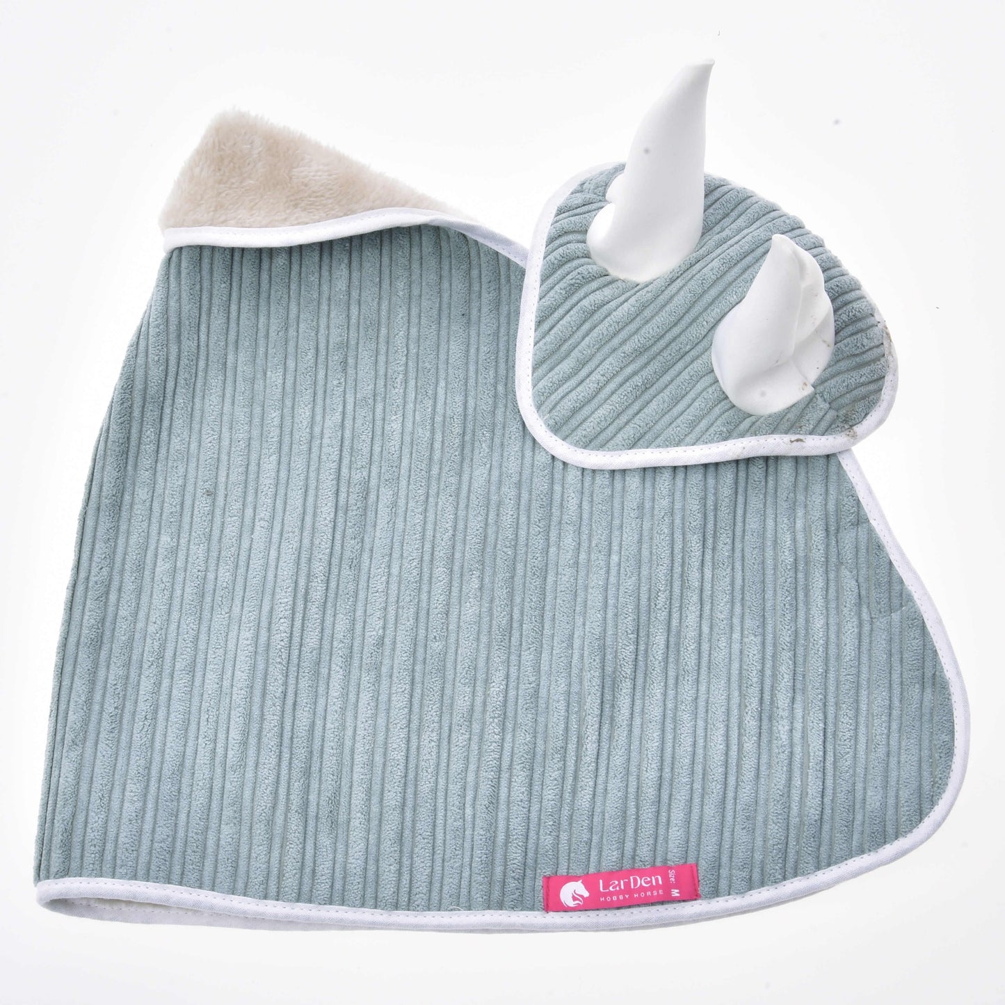 A soft, ribbed, light-gray square with white trim from the Set Manchester Little Green by Hobby Horse LarDen features two plush white horns, a beige fuzzy corner, and a pink "Lazhen" label. It’s laid flat on a white background.