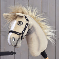 Hobby Horse Ivory Dream avec Licol noir - taille XS de Hobby Horse LarDen, tenu par une personne, avec robe beige clair, marques blanches sur le visage, crinière duveteuse et licol noir, sur fond en bois.