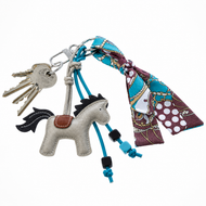 Porte-clés Horse Grey de Hobby Horse LarDen sur un anneau avec un jeu de clés, des cordons perlés bleus et une écharpe à motif bleu, marron et blanc nouée à l’anneau.