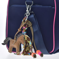 Porte-clés Horse Brown de Hobby Horse LarDen, décoré d’une écharpe colorée et de perles orange et roses, accroché à un sac bleu marine avec bordure rose et sangle bleue, parfait pour les fans de Hobby Horsing.