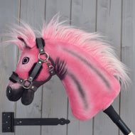 A limited edition Hobby Horse LarDen Pinkie with a glittery halter from Hobby Horse LarDen is mounted on a stick and positioned against a gray wooden wall.
