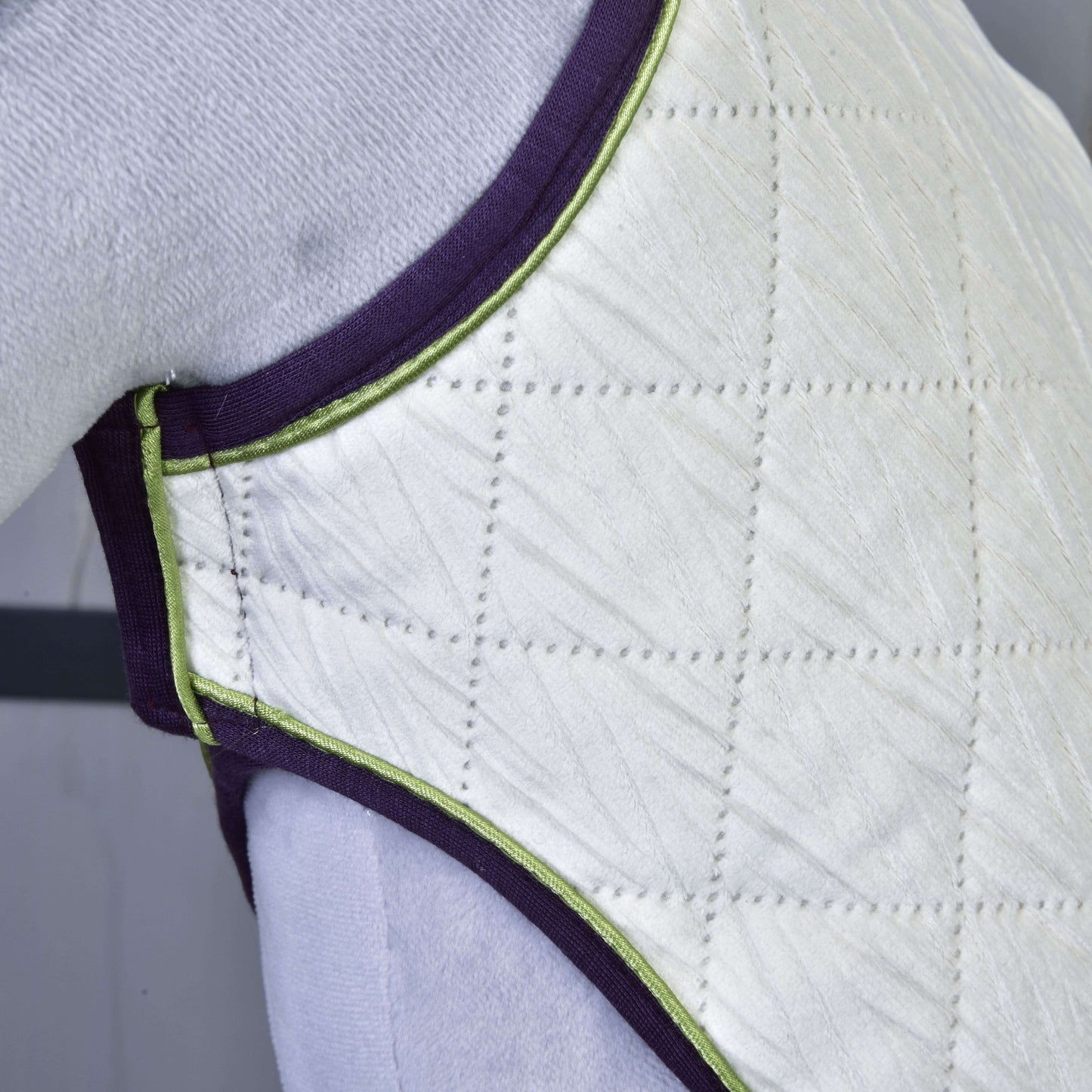 Close-up of quilted, padded white fabric with purple and green trim in a diamond pattern, covering a curved surface—part of the Set Leonardo by Hobby Horse LarDen.