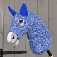 A close-up of the Hobby Horse LarDen "Hobby Horse protective suit See," featuring blue and white PES fabric with blue ears and gray muzzle, mounted on a wooden stick against a gray wooden background.