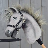 Hobby Horse Prestige avec Licol noir, taille XS de Hobby Horse LarDen, au design en peluche gris avec crinière hérissée et licol noir, inspiré de l’élégance d’un cheval de sport Warmblood anglais. Il est monté sur un bâton en bois et présenté sur un fond de panneaux en bois.
