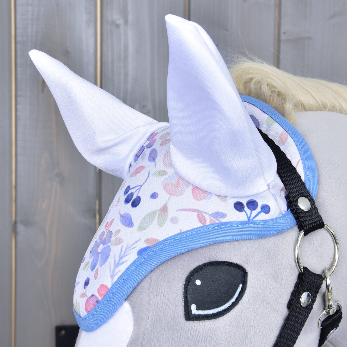 Gros plan du Set Vanessa NEW de Hobby Horse LarDen : tête de Hobby Horse en peluche avec bonnet d'oreilles floral pastel à oreilles blanches douces, sur fond en bois.