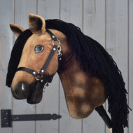 The Hobby Horse LarDen "Hobby Horse Stormy with Black Halter" features a brown plush Hanoverian design with a black yarn mane, black halter, and white markings, shown mounted on a stick against a gray wooden background.